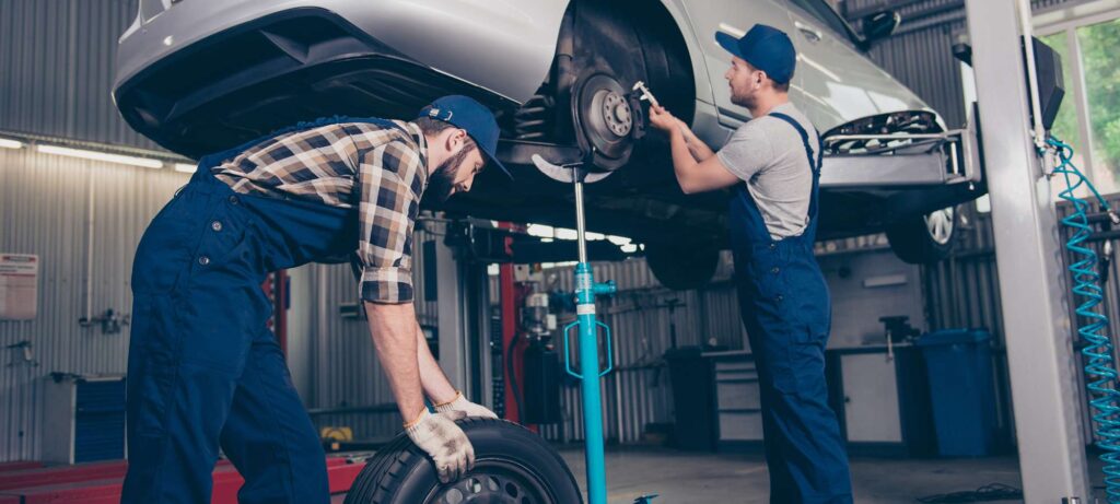 two men fitting the wheel of the car in the garage